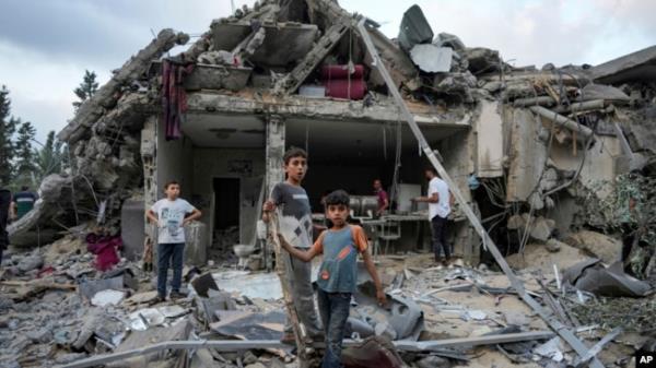 FILE - Palestinians look at the destruction after an Israeli airstrike in Deir al Balah, Gaza Strip, April 30, 2024.