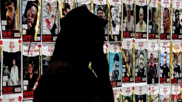 A person walks past posters of Israeli hostages held in Gaza since the October 7 attacks by Palestinian militants, during a protest by the families of the hostages and their supporters, in Tel Aviv on April 25, 2024.