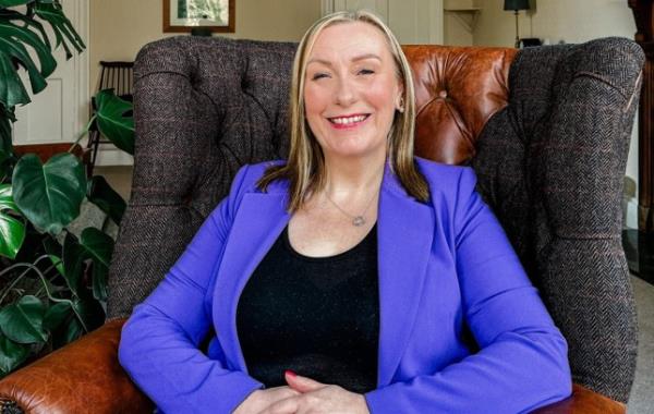 Julie Bale sitting in a chair wearing a blue jacket