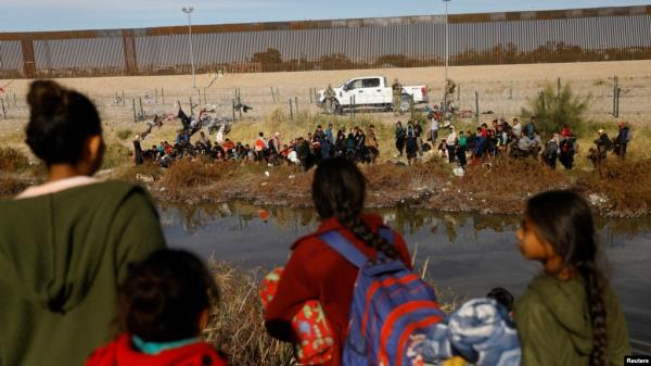 FILE - Migrants seeking asylum in the United States gather on the banks of the Rio Bravo River, as the Texas Natio<em></em>nal Guard waits at the border between the United States and Mexico, as seen from Ciudad Juarez, Mexico, Dec. 5, 2023. 