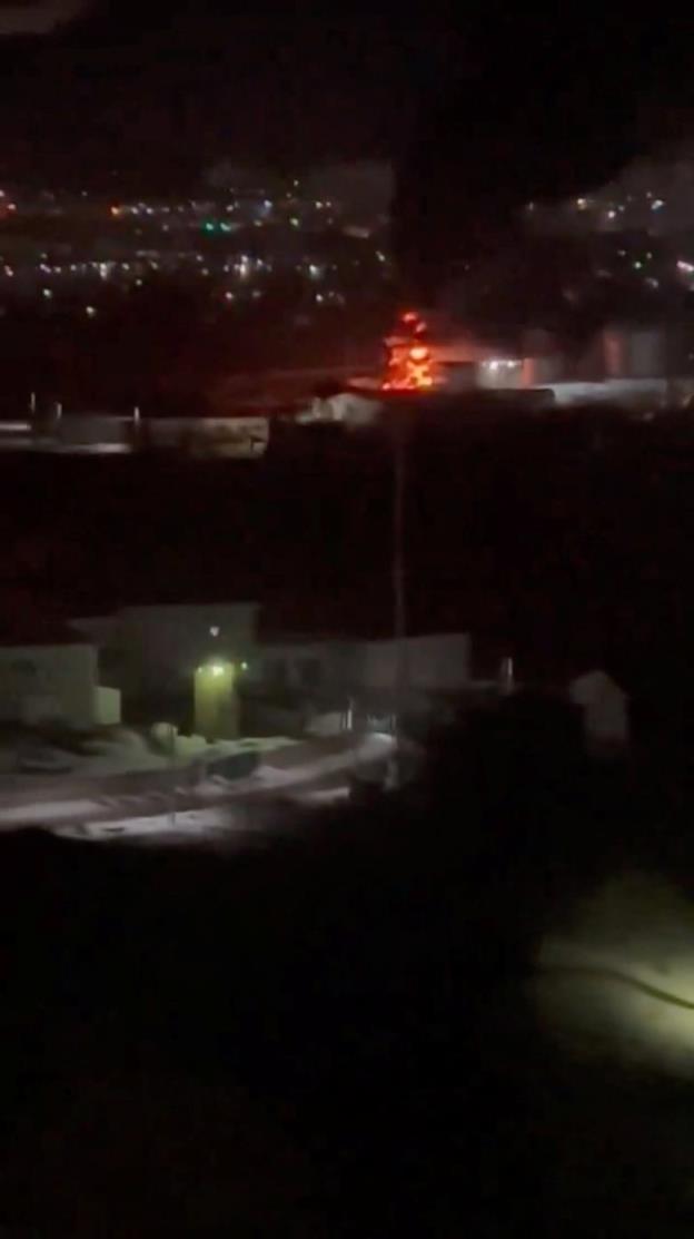 A fire burns in the distance at night.