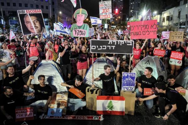 people at a protest with Lebanese flags and signs in Hebrew