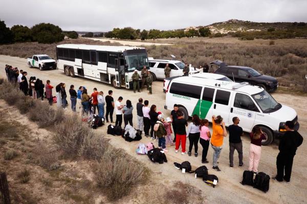 Migrants are processed by Border Patrol agents after crossing the border into Jacumba Hot Springs, California