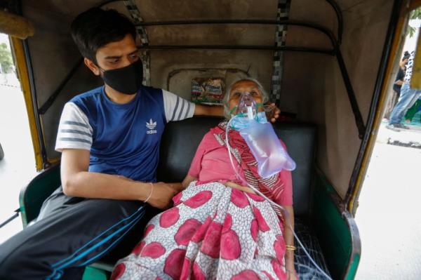 A COVID-19 patient wearing oxygen mask waits inside an auto ricksha to be attended and admitted to a dedicated COVID-19 government hospital in Ahmedabad, India, Saturday, April 17, 2021. The global death toll from the coro<em></em>navirus topped a staggering 3 million people Saturday amid repeated setbacks in the worldwide vaccination campaign and a deepening crisis in places such as Brazil, India and France. (AP Photo/Ajit Solanki)