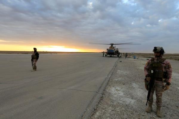 Iraqi security forces are seen at Ain al-Asad airba<em></em>se near a military helicopter in Anbar province