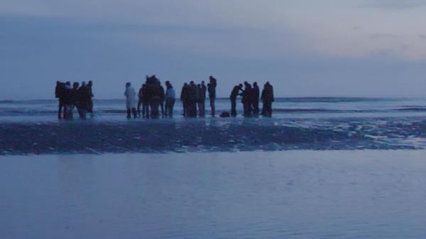 Migrants wait for a dinghy as they prepare to cross the Channel to reach the UK.