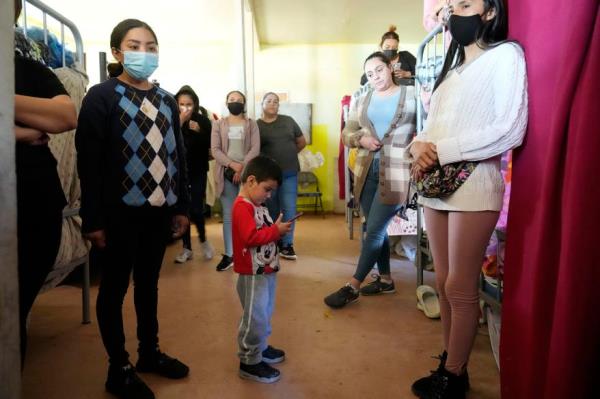 Carlos Anto<em></em>nio Corza Reyes, bottom center, looks as his phone next to his mother Maria Del Rocio Reyes inside a shelter for migrants.
