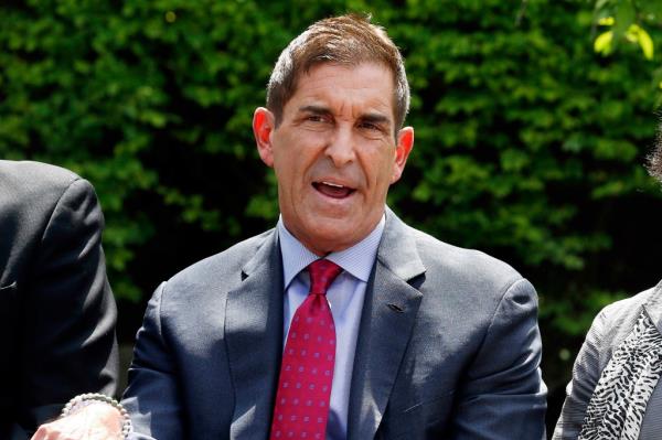 Jeff Klein in a suit and tie looking at the camera with a green background