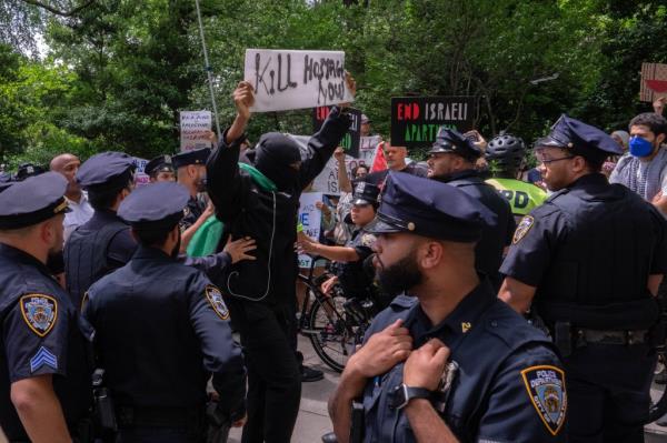 A NYPD officer moving a protestor holding a 'Kill Hostages Now' sign back into the crowd during Palestine protests, Israel Day parade, New York City