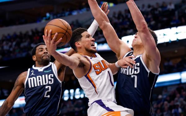 Devin Booker #1 of the Phoenix Suns goes to the basket as Kyrie Irving #2 and Dwight Powell #7 of the Dallas Mavericks