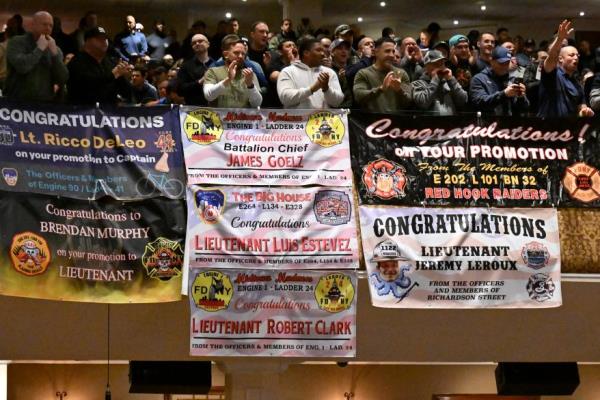 Family and friends with signs co<em></em>ngratulating the newly promoted firefighters at the ceremony.