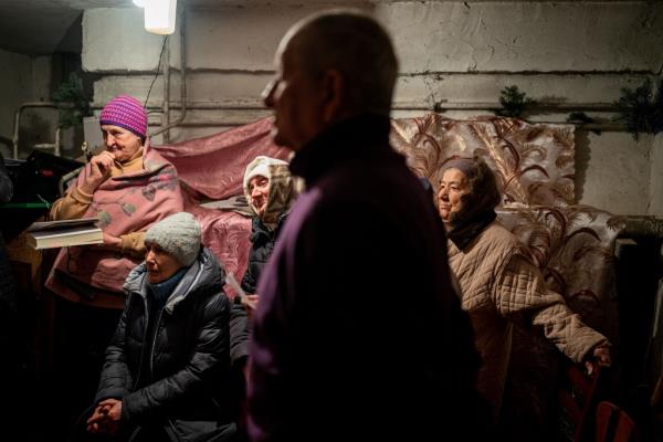 Worshippers pray during an Orthodox Christmas mass in a ba<em></em>sement shelter.