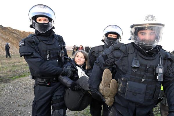 Police officers carry Swedish climate activist Greta Thunberg away from the edge of the Garzweiler II opencast lignite mine during a protest action by climate activists after the clearance of Luetzerath, Germany, Tuesday, Jan. 17, 2023.