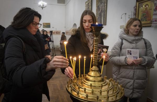 People light candles to commemorate British volunteers Chris Parry and Andrew Bagshaw, killed in Ukraine's war-hit east, during commemorating service in a refectory near St. Sophia Cathedral in Kyiv, Ukraine, Sunday, Jan. 29, 2023. Andrew Bagshaw was a dual New Zealand and British citizen who was killed along with British colleague Chris Parry while attempting to rescue an elderly woman from the town of Soledar when their car was hit by an artillery shell.