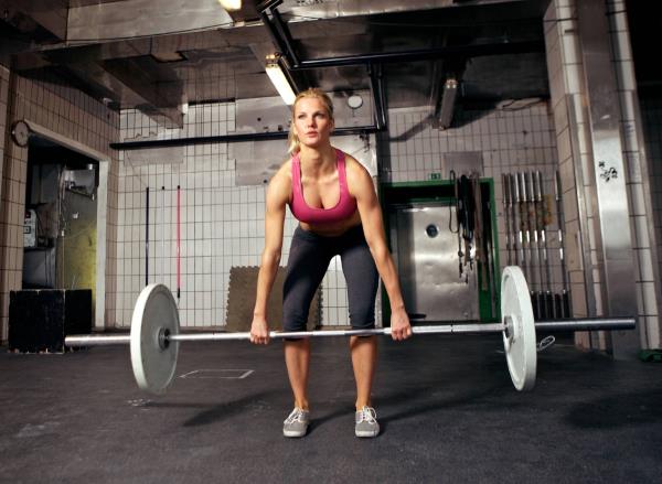 woman doing barbell deadlift, co<em></em>ncept of easy glute exercises to get rid of pancake butt