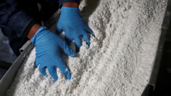 An employee grabs carbo<em></em>nate lithium after being processed at the Rincon Mining lithium pilot plant, at the Salar del Rincon salt flat, in Salta, Argentina on 12 August 2021. Photo: REUTERS/Agustin Marcarian