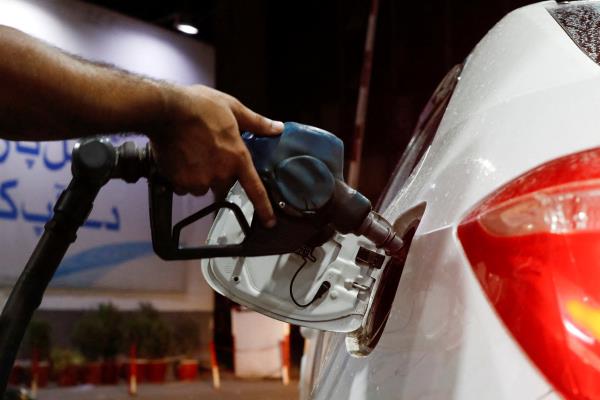 A worker holds a fuel nozzle to fills fuel in a car, after the government announced the increase of petrol and diesel prices