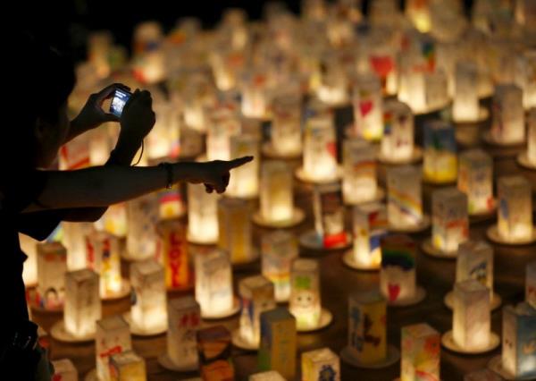 People look at candles during a candlelit memorial event to mourn the victims of the 1945 atomic bombing at Nagasaki's Peace Park in Nagasaki