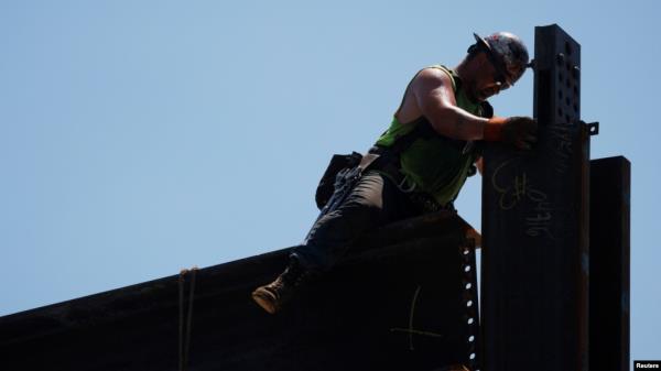 FILE - A worker installs steel beams on high-rise building under co<em></em>nstruction during a summer heat wave in Boston, June 30, 2021. 