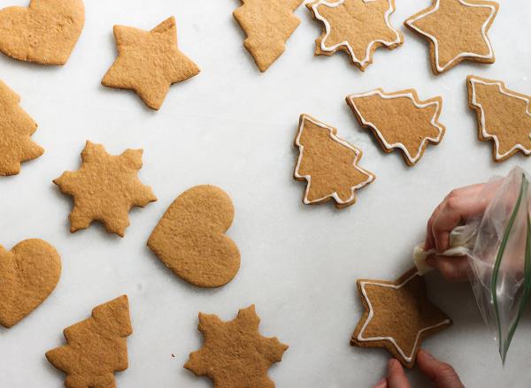 icing the edges of gingerbread coo<em></em>kies on a marble counter