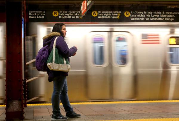 A person waits on a platform to board a subway train at the 34th Street - Herald Square station