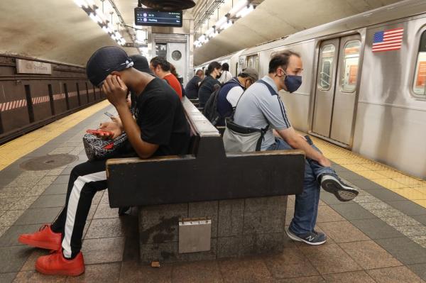 People wait to board a 7 train at the 42nd St Grand Central subway station
