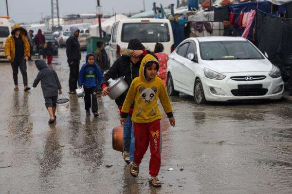Displaced Palestinians walk to get food rations at a makeshift tent camp in Rafah in the southern Gaza Strip on Feb. 2.