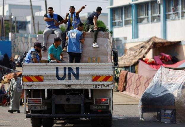 Six men on the back of a flatbed truck. Several are wearing blue UN vests.