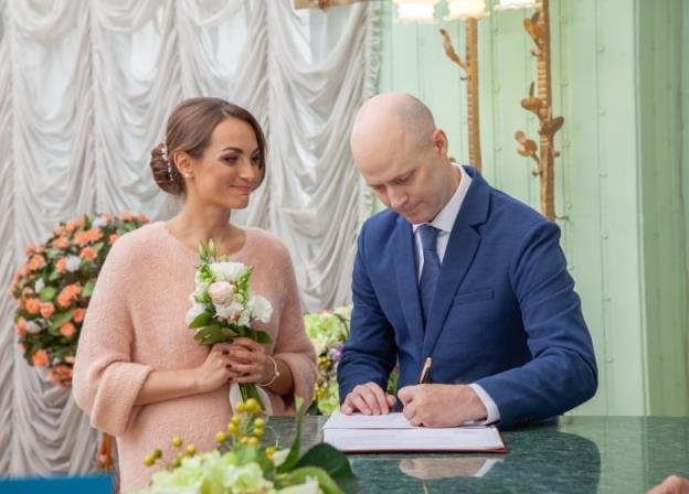 A man and woman stand together signing marriage papers