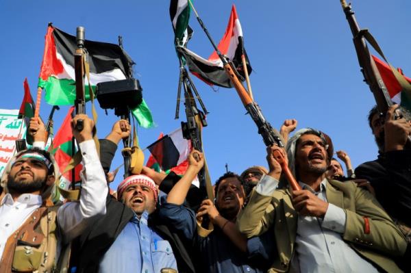 People brandish rifles and Palestinian flags during a march to show solidarity with the Palestinians of the Gaza Strip on October 18, 2023, in the Houthi-co<em></em>ntrolled Yemeni capital Sanaa