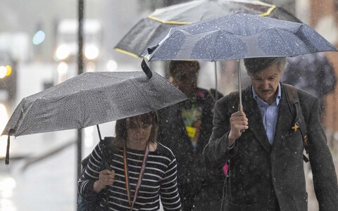 People with umbrellas during heavy rain in Lo<em></em>ndon in August this year