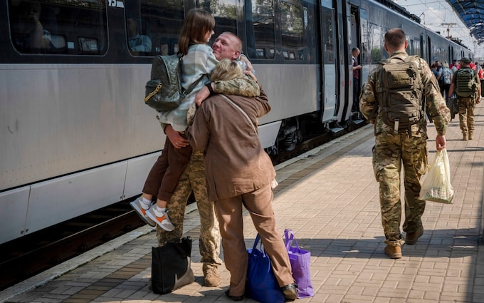 A Ukrainian serviceman hugs his wife and the daughter at the railway station in Sloviansk, Do<em></em>netsk region
