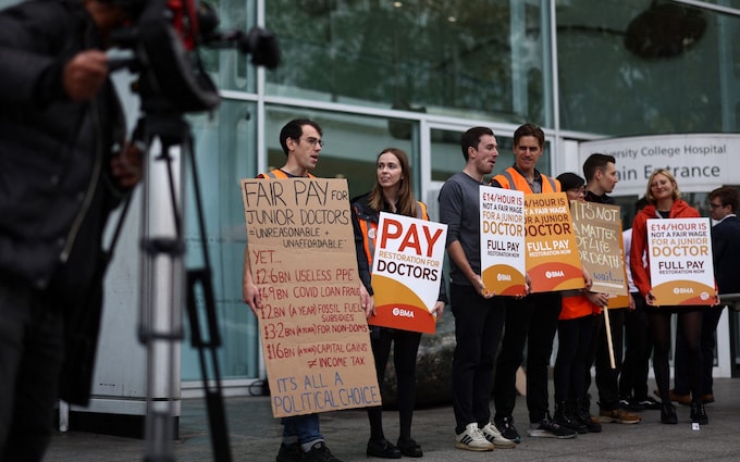 People hold placards on a picket line outside University College Hospital