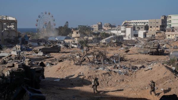 IDF soldiers move through a demolished Gaza neighborhood on Tuesday.