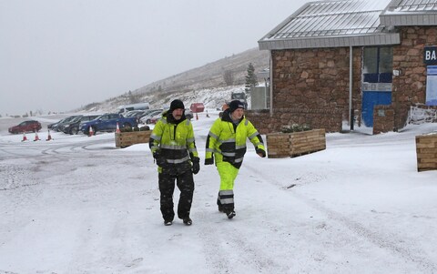 Workmen walk through snow blizzards at Glenmore in the Scottish Highlands as storm Ciaran hits the UK