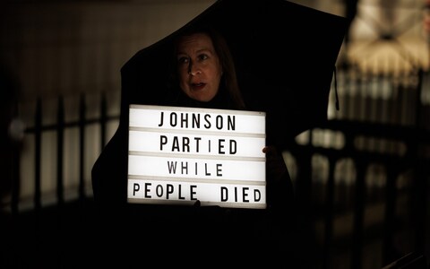 A woman protests ahead of the arrival of Former British Prime Minister Boris Johnson to the Covid Inquiry on December 7, 2023 in London, England. Britain's former Prime Minister will be questio<em></em>ned during phase 2 of the Covid-19 Inquiry over government decision-making during the pandemic.