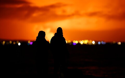 People watch as the night sky is illuminated