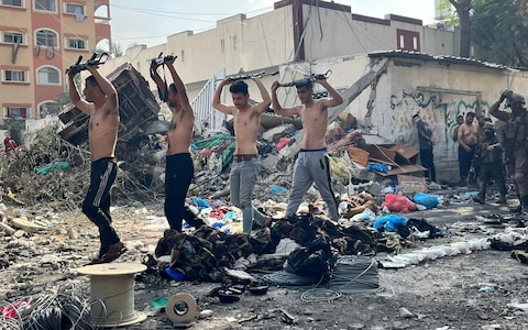 Palestinian men carry weapons as they are taken for questio<em></em>ning by the IDF
