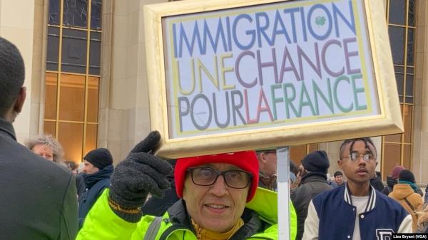 A protester of Algerian descent brandishes a sign reading 