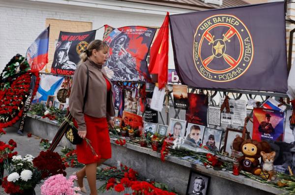 A woman visits a makeshift memorial for Yevgeny Prigozhin.