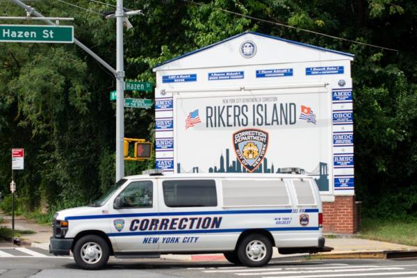 A Department of Correction van outside the Rikers Island sign.