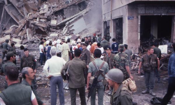 A crowd of soldiers and aid givers stand amid the destruction and damage at the scene of the suicide bombing of the American Embassy, Beirut, Lebanon, April 18, 1983.