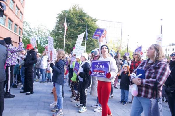 Protesters hold signs reading 