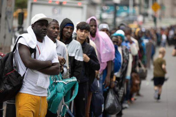 Migrants wait on a sidewalk outside 26 Federal Plaza in New York, Tuesday, June 27, 2023.