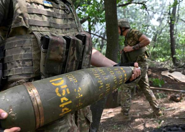 A Ukrainian artilleryman carries a 155 mm shell to fire a M777 howitzer toward Russian positions