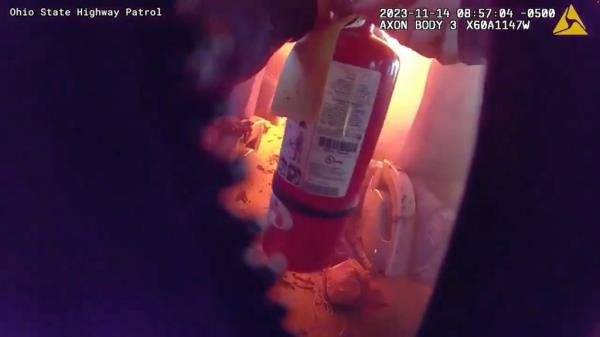 The highway patrol officer could be seen with his fire extinguisher on the burning bus.