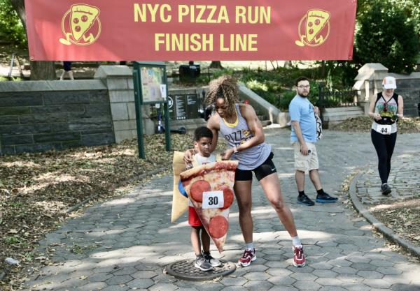 Child dressed in pizza costume and woman at the pizza run finish line
