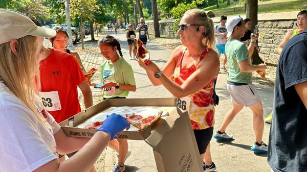 Woman picking up slice of pizza from box
