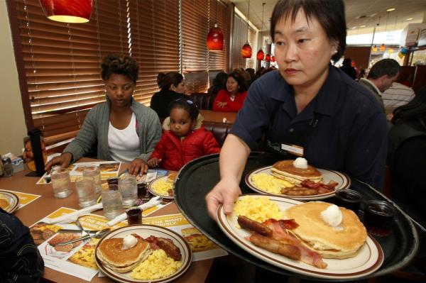 Woman serving breakfast to customers at a Denny's
