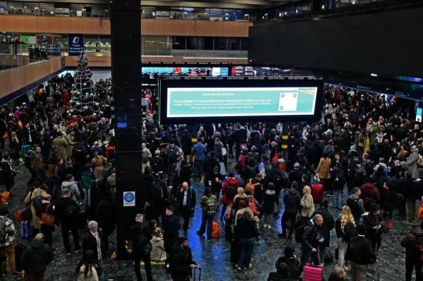Rail travellers stand beneath an electro<em></em>nic information board displaying a message from Network Rail a<em></em>bout damaged overhead wires